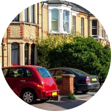 Three cars parked in the driveways of three houses photographed from the road.
