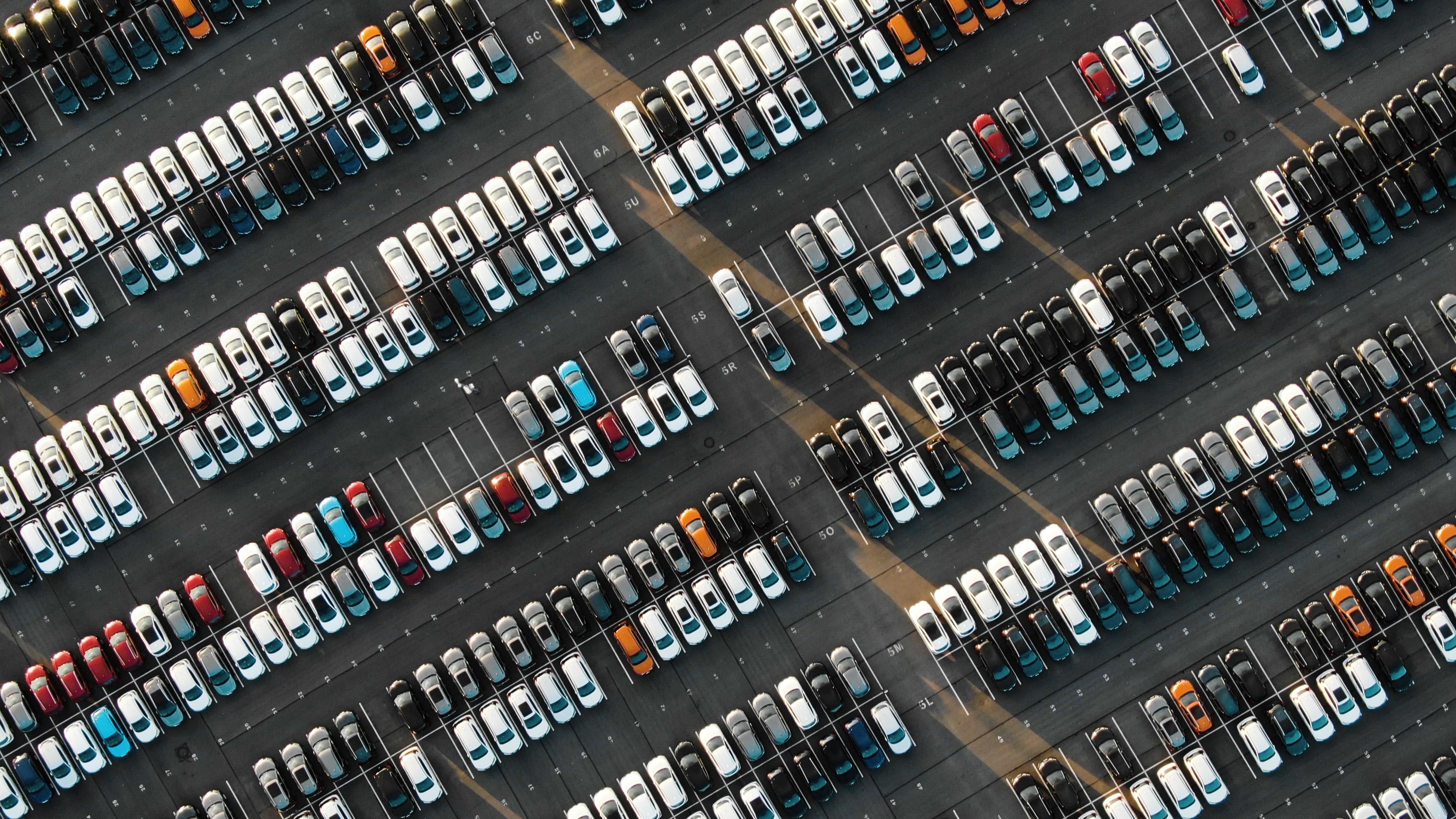Aerial view over a couple hundred cars in a car park.