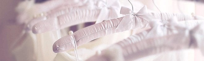 Close-up of white satin wedding dress hangers on a rail.