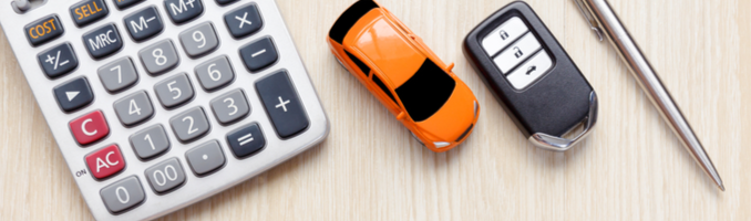 A calculator next to a small model car and a car key.