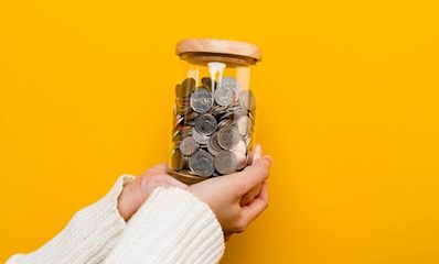 A child's hands putting coins into a piggy bank