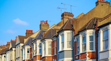 A row of terraced houses somewhere in the UK against a clear blue sky