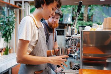 Image shows a barista making coffee in a coffee shop