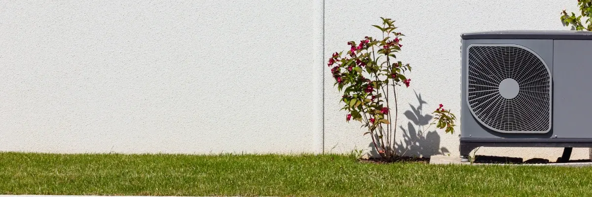 Een buitenunit van een warmtepomp in een tuin