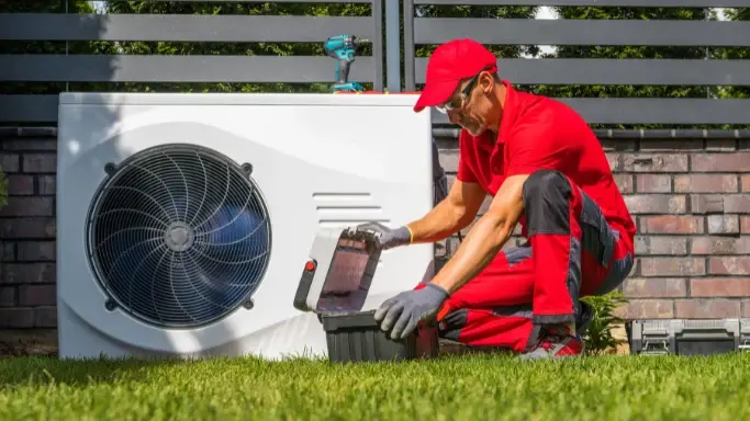 Warmtepomp installateur in tuin. Rode outfit, Makita boor