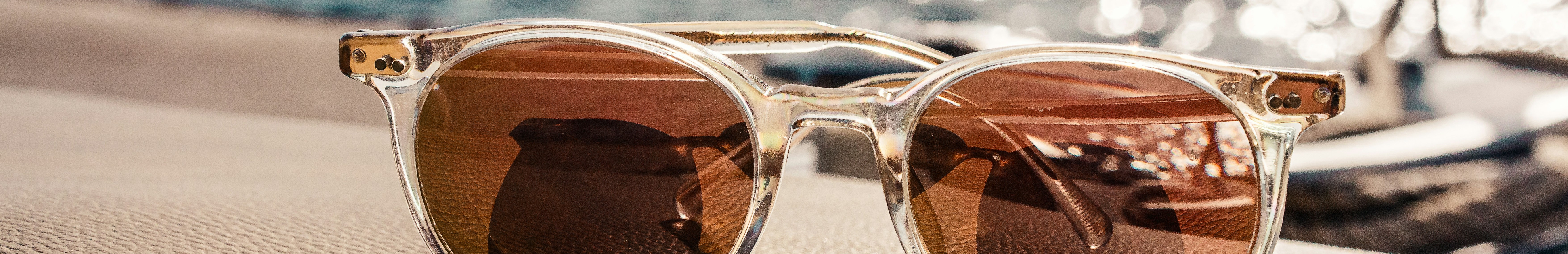 Lunettes de soleil aux verres teintés posées, avec la mer en arrière-plan.