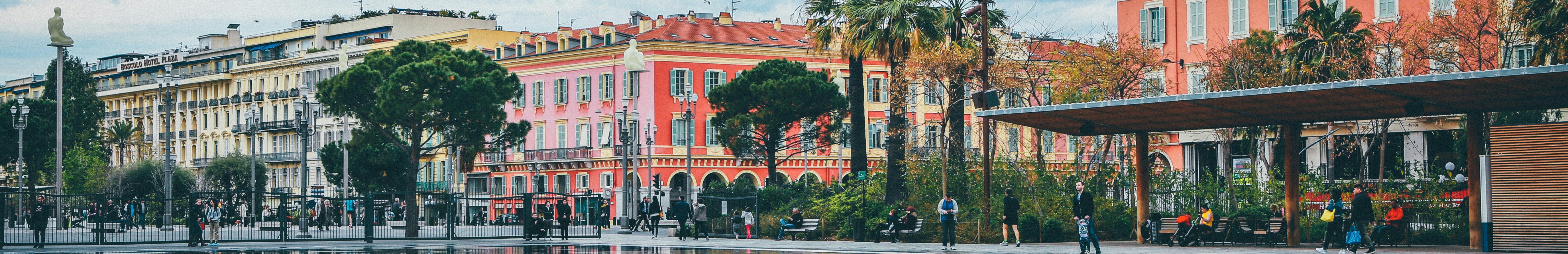 Bâtiments jaunes et rouges partiellement cachés par des arbres et des palmiers.