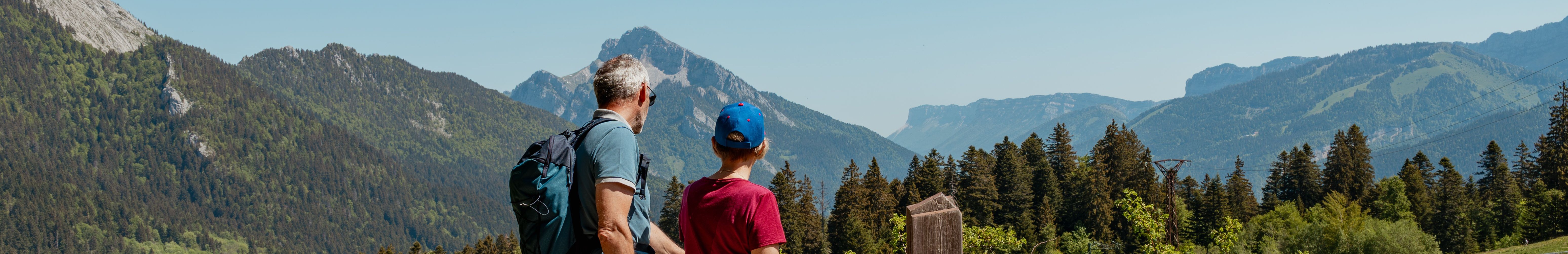 Un couple en randonnée avec leur chien à la montagne.