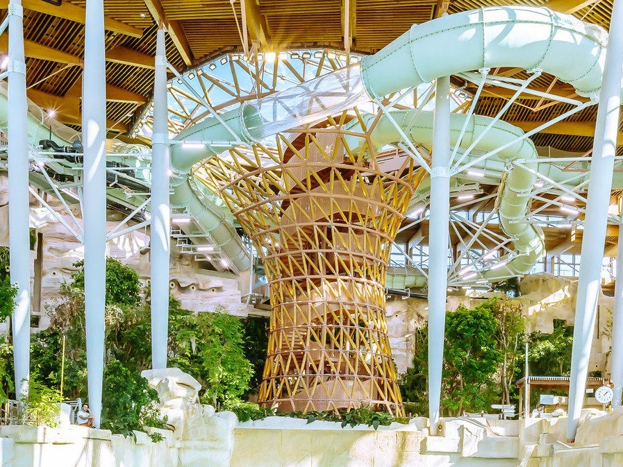 Centre Parcs intérieur tropical avec toboggans et végétation luxuriante.