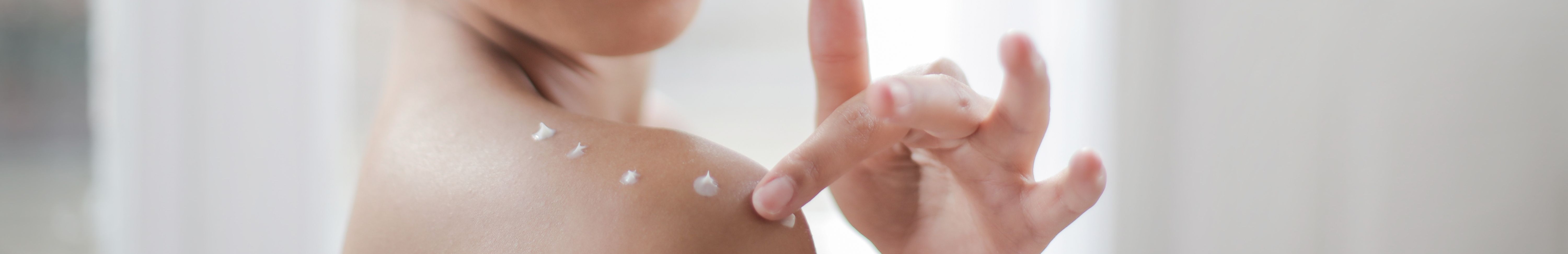 Femme appliquant un soin sur sa peau.