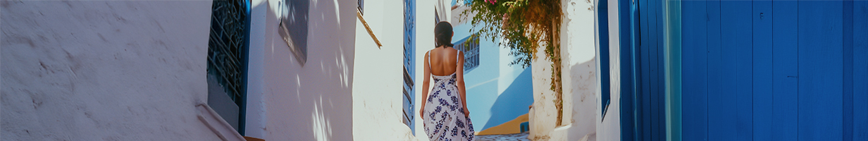 Femme en robe blanche et bleue dans les ruelles de Sidi Bou Said en Tunisie.