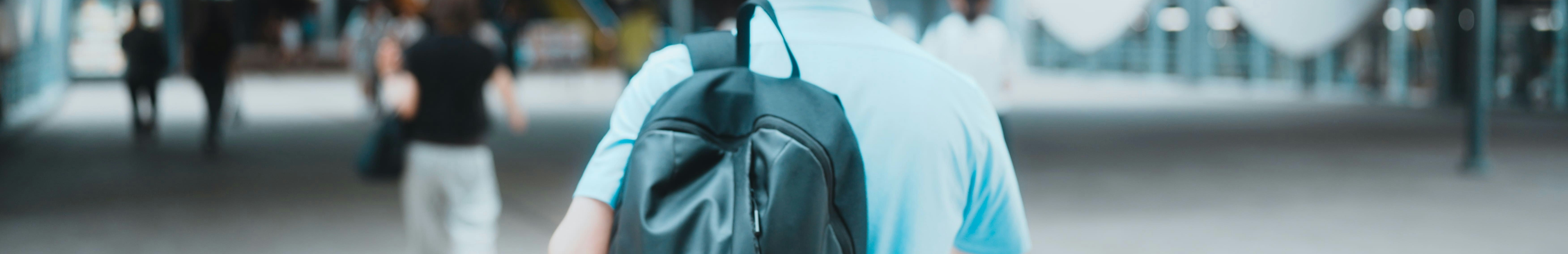 Homme portant un sac à dos noir à l'épaule.