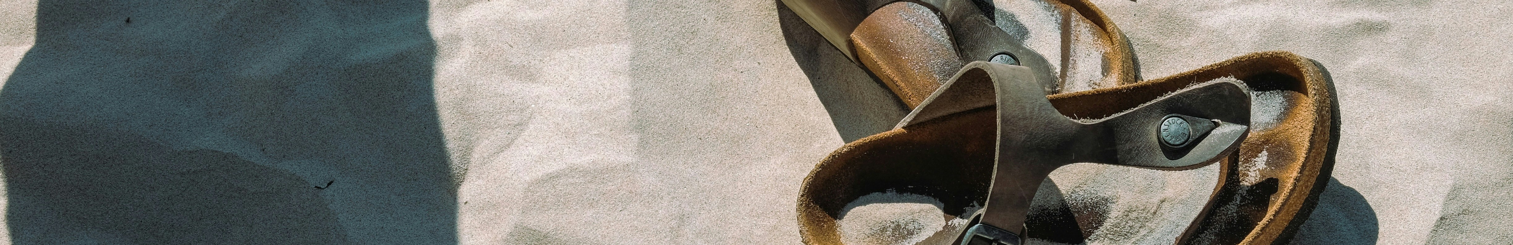 Sandales posées sur le sable d’une plage.
