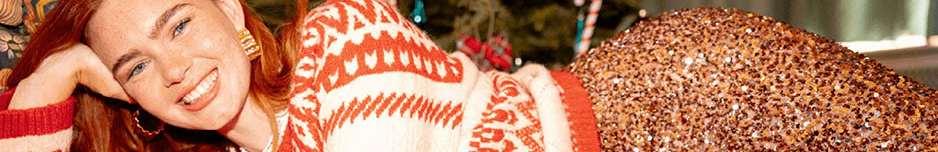 Jeune femme rousse en habits festifs Bonobo devant un sapin.