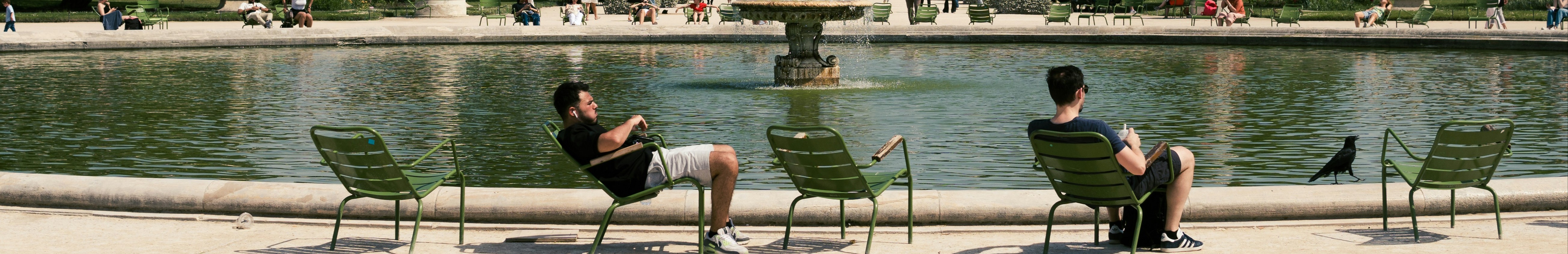 Hommes assis sur des chaises devant une grande fontaine.