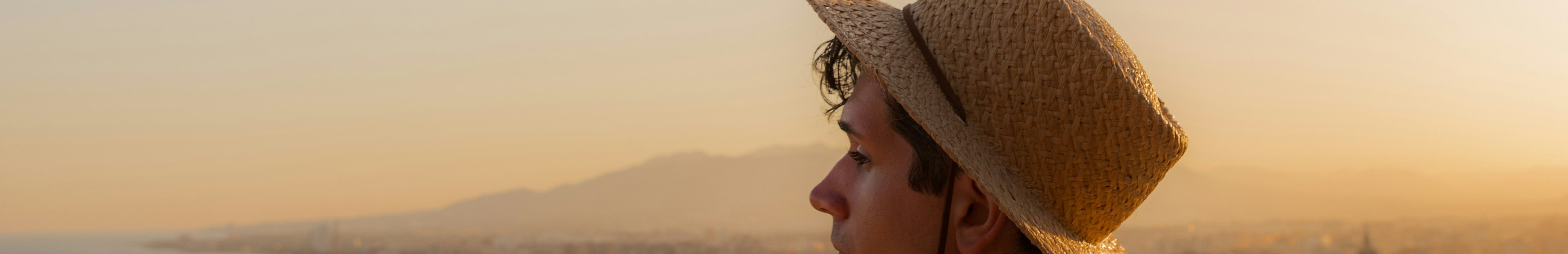 Homme vu de dos, portant un chapeau et admirant le paysage.