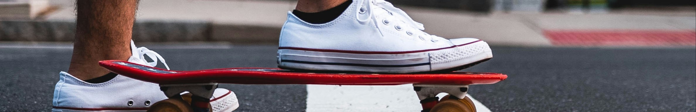 Homme portant des chaussures blanches debout sur un skateboard.