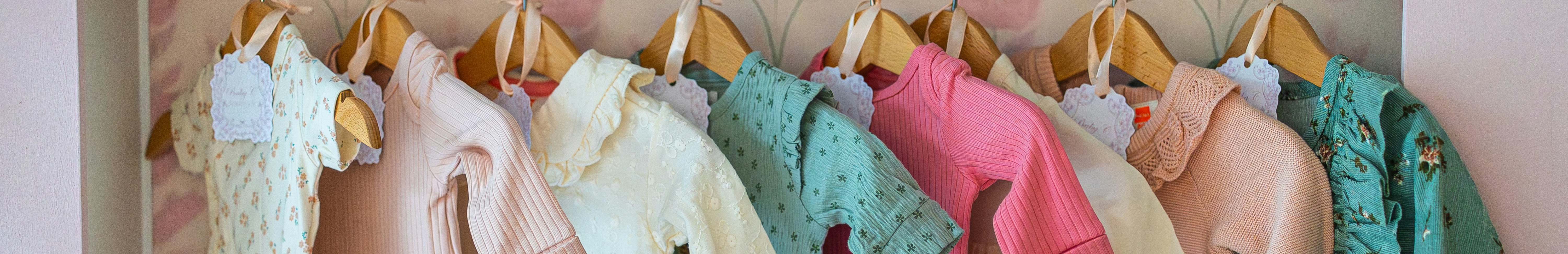Vêtements de bébé colorés accrochés sur des cintres.