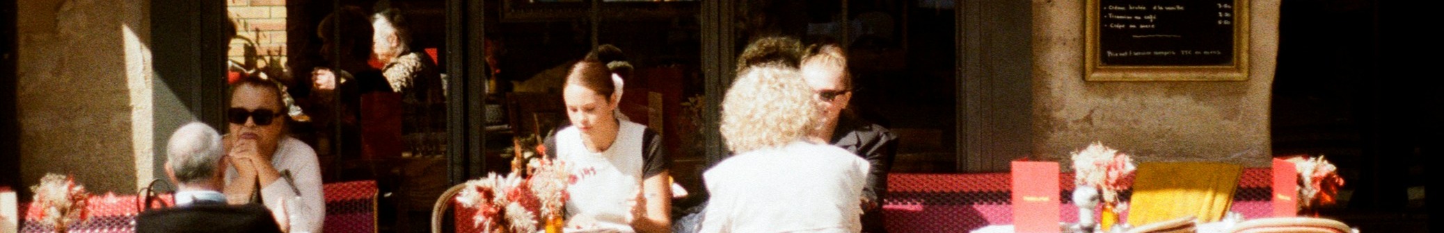 Personnes assises en terrasse devant un restaurant parisien.