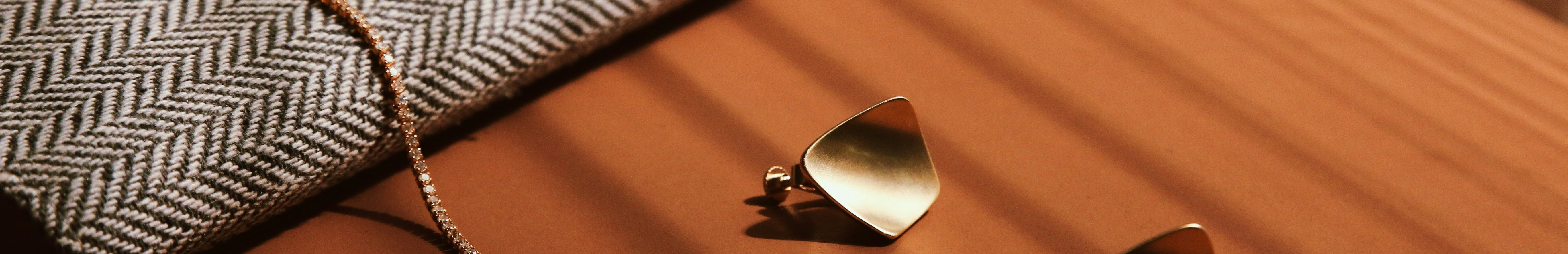 Paire de boucles d'oreilles et bracelet en or posés sur une table en bois.