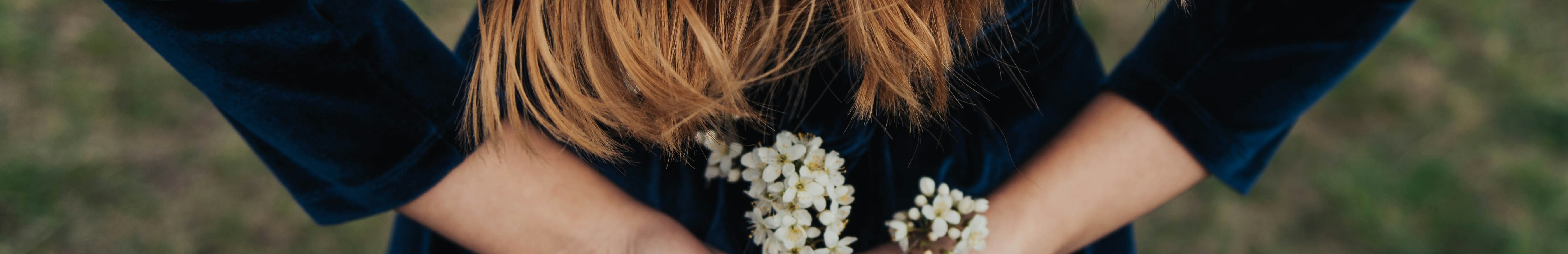 Femme portant une robe bleue en velours, tenant un bouquet de fleurs.