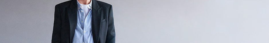 Homme portant blazer noir et chemise bleue claire.