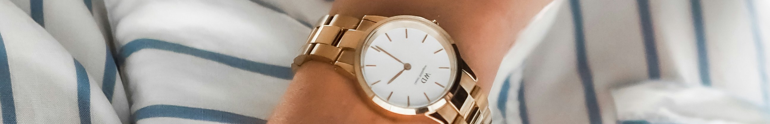 Zoom sur une montre dorée au poignet d'une femme.