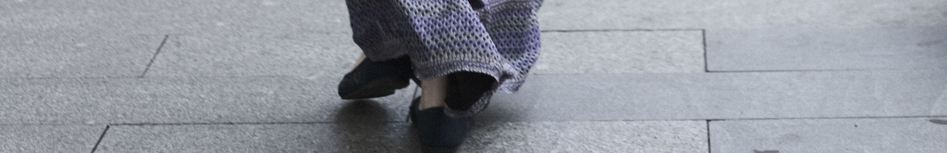 Femme vue de dos, portant une jupe longue, marchant dans une rue.