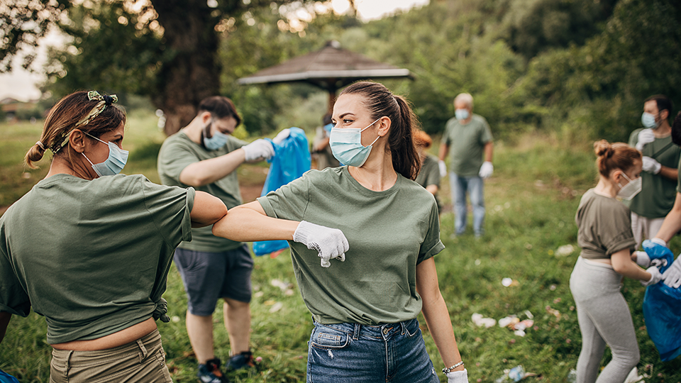 A group of volunteers with surgical masks cleaning up litter. 