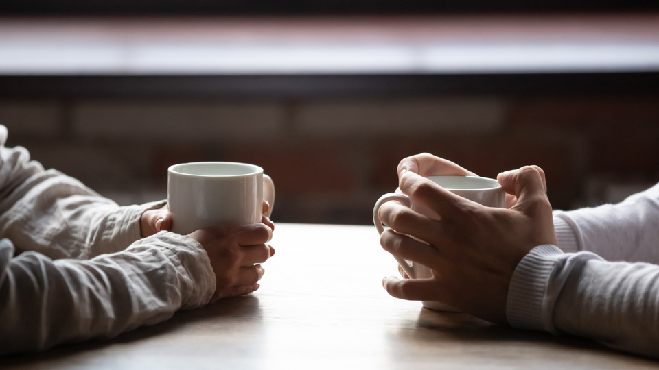 Two pairs of hands holding mugs