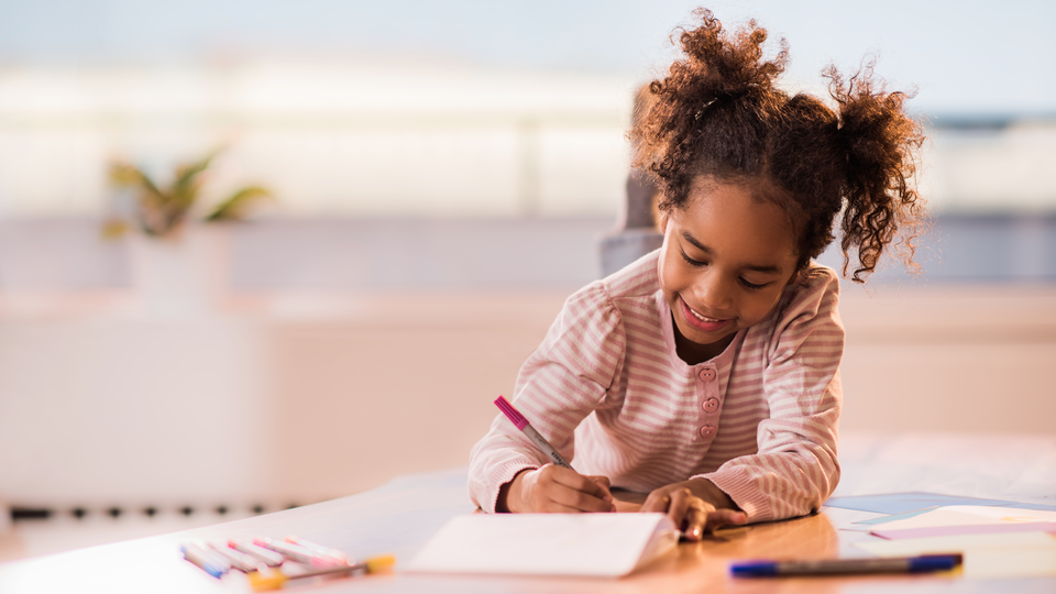 Young girl writing with colored markers.