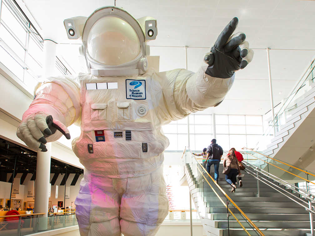 Image of the giant astronaut with people walking up the stairs nearby