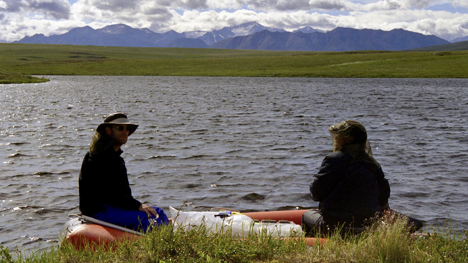 Two people on a dinghy on arctic lake.