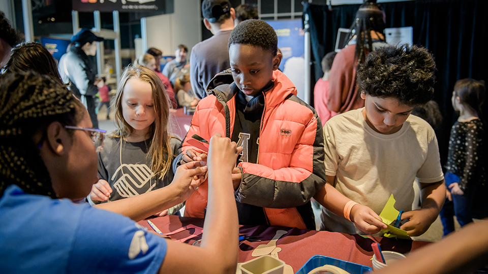 Youth conducting experiments with a volunteer during Science Fusion. 