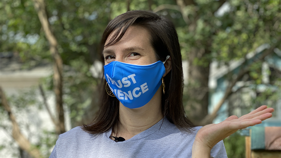 A woman wearing a Science Museum of Minnesota branded "Trust Science" face mask.