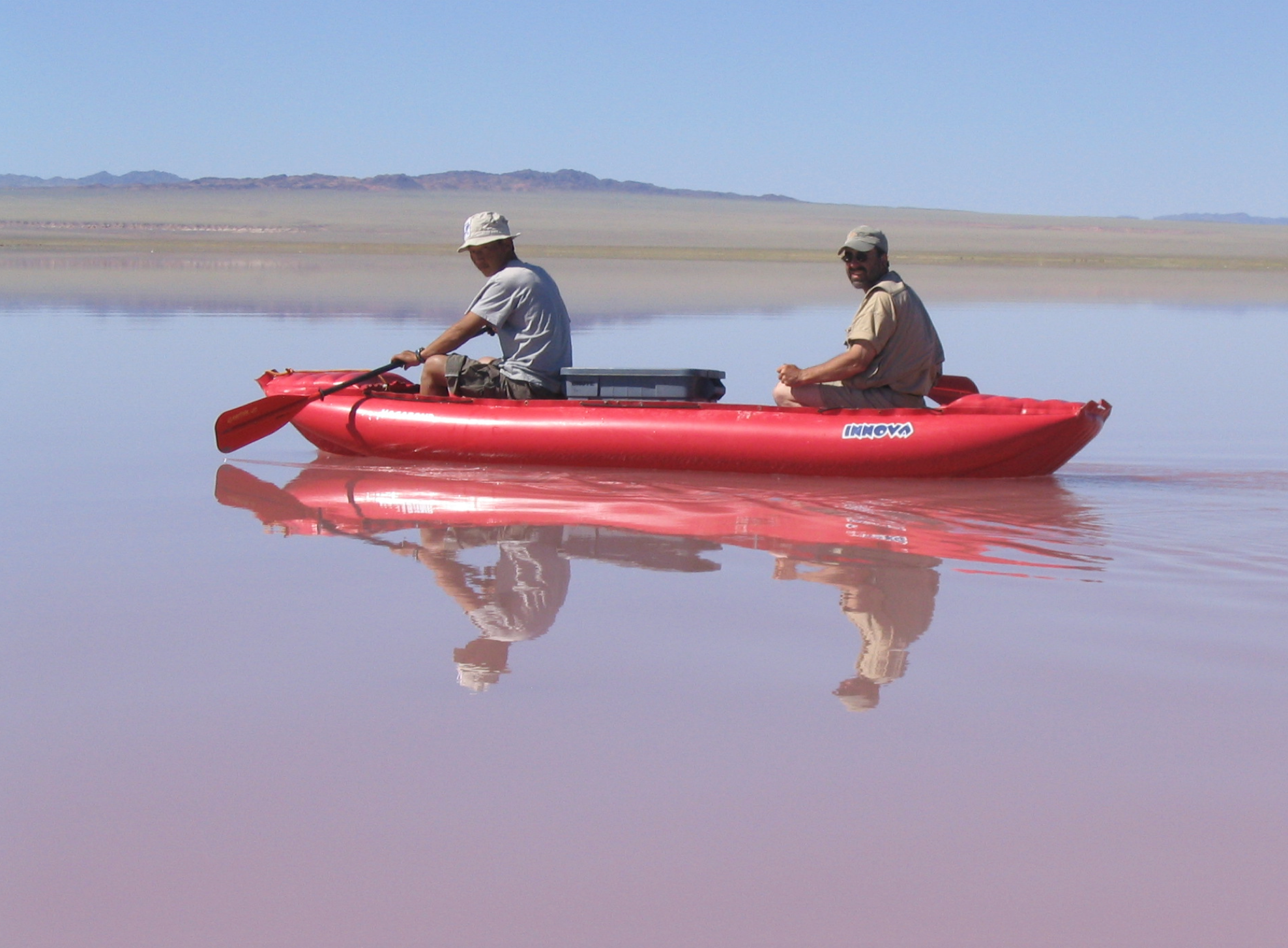 Two scientists on a red-colored lake in Mongolia