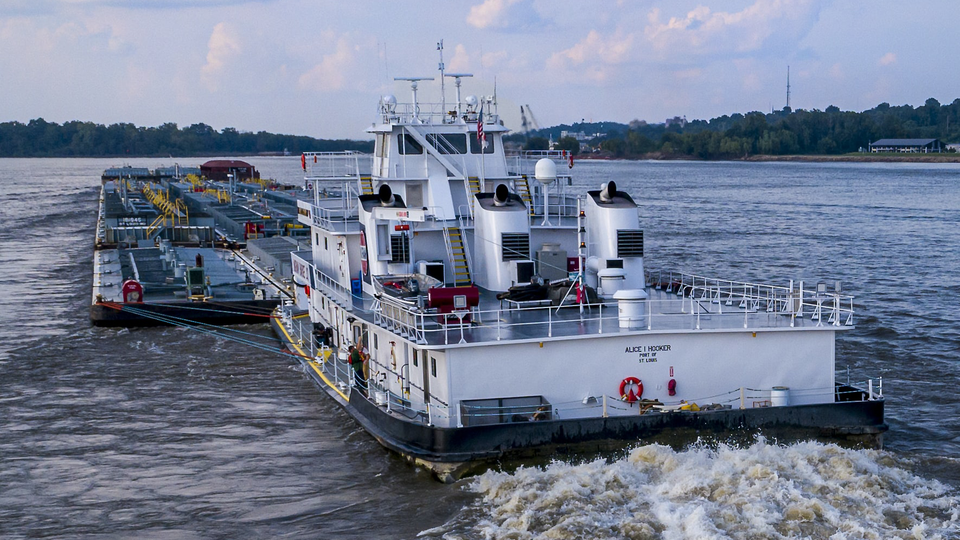 A white tugboat sails down the river in St. Paul.
