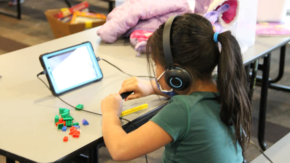 Child playing with building pieces while watching and listening to a screen 