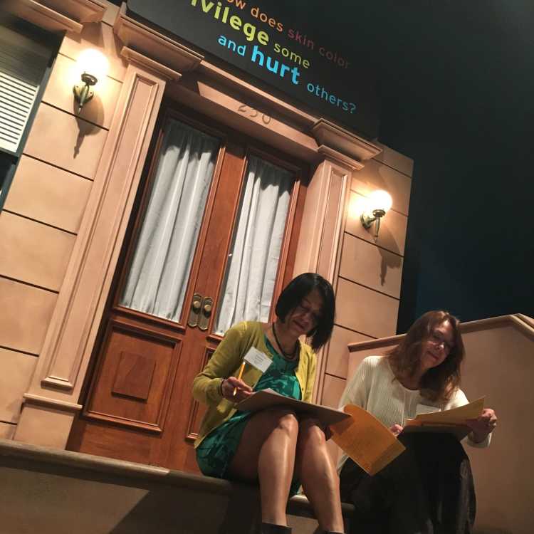 PAGE participants sit on the steps of a RACE exhibit.