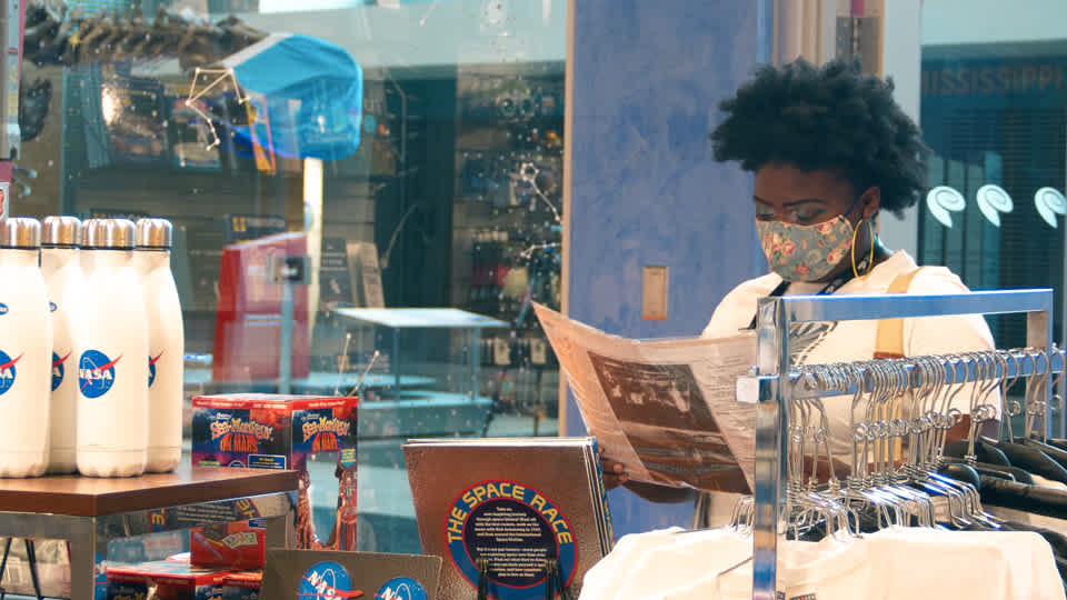 Woman holding a paper item while shopping at the Explore Store