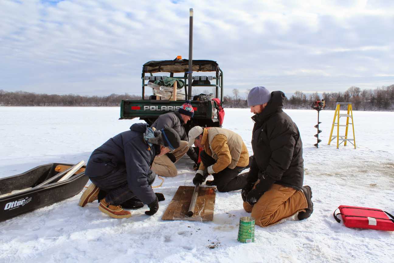 January 2015: The crew uses an auger to drill holes through a foot of ice on Miller Lake, in Carver County. Gathered around the hole, they perform some calculations, plunge a tube into the water and into the mud on the bottom, and then pull it back up. Winter is a great time to take sediment samples. Once the ice is thick enough, it provides a much steadier and more spacious working surface than a boat bobbing on liquid water. There’s also no risk of drifting away from the study site. 