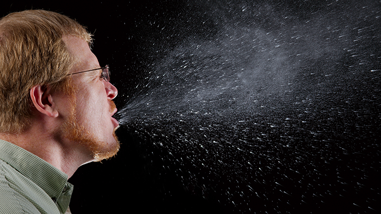 A man coughing a visible stream of droplets. 