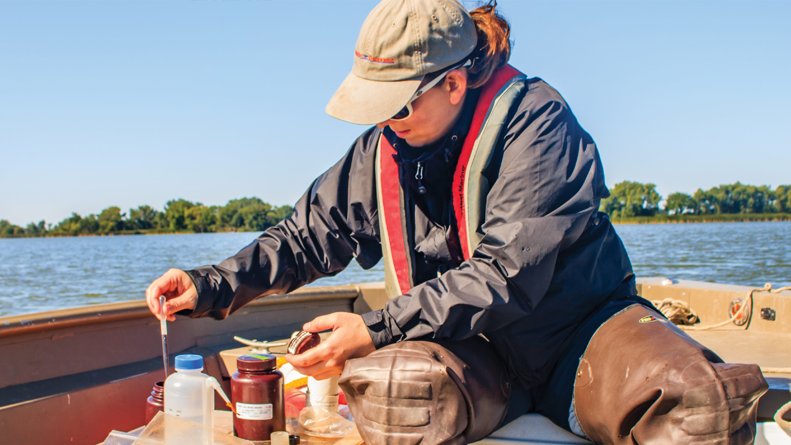 A scientist collecting samples while boating on the St Croix river. 