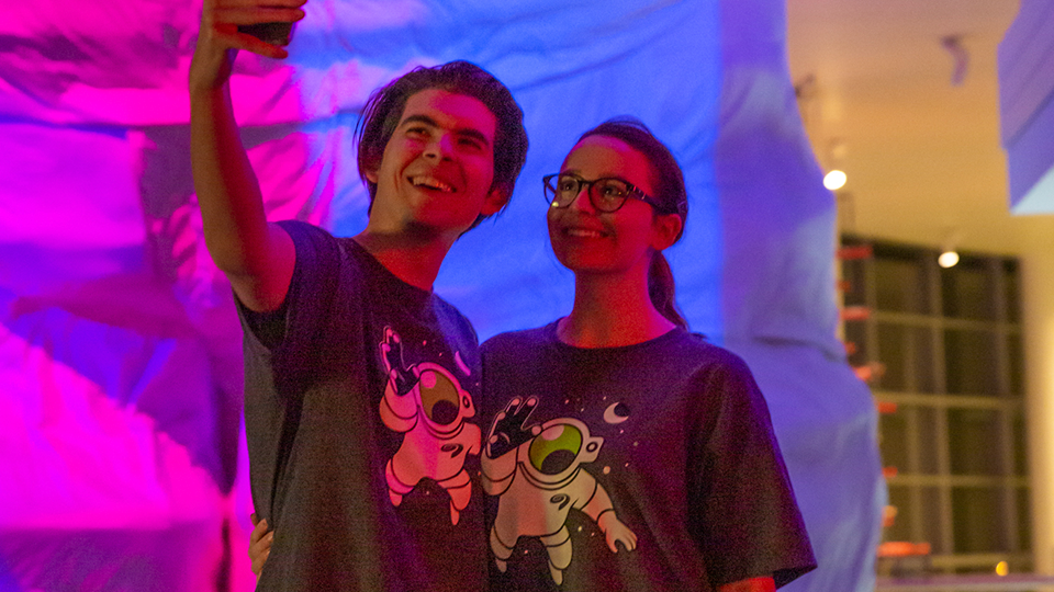 A couple wears museum t-shirts featuring the giant astronaut. 