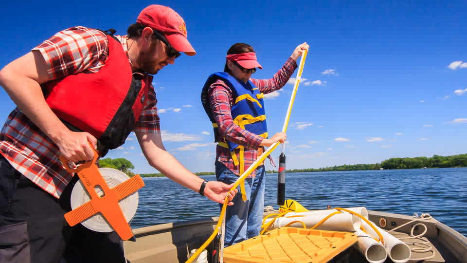 Dr. Adam Heathcote and Alaina Fedie prepare to deploy research buoys in Madison Lake to continuously monitor lake conditions as part of a study into harmful algal blooms. (Greg Seitz/Science Museum)