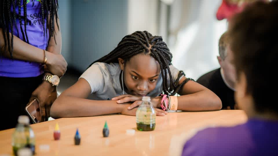 Image of girl looking at experiment with water in water bottles and food dye coloring