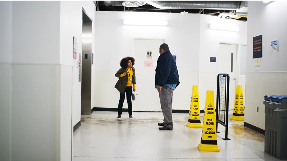 Two people interacting in a hallway waiting for an elevator. 