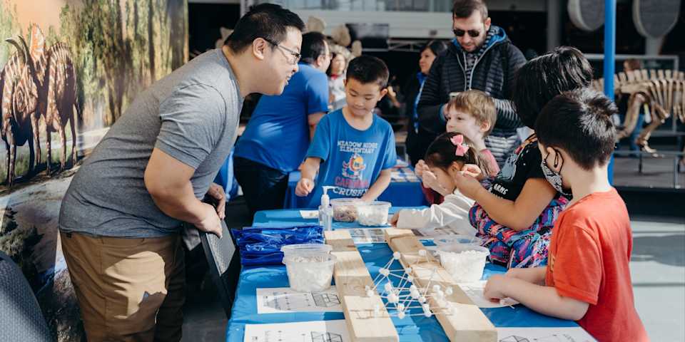 An individual running a table tells a group of children about something