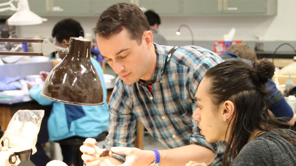 Dr. Alex Hsatings showing a fossil to a person in the paleontology lab