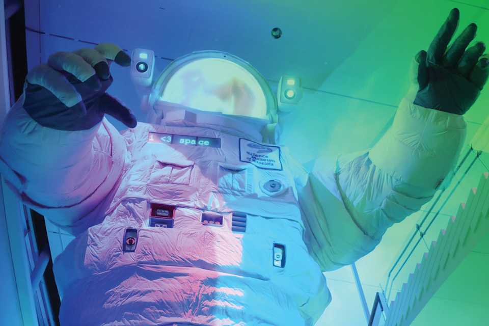 Image of the giant astronaut at the Science Museum with a family walking up the stairs nearby